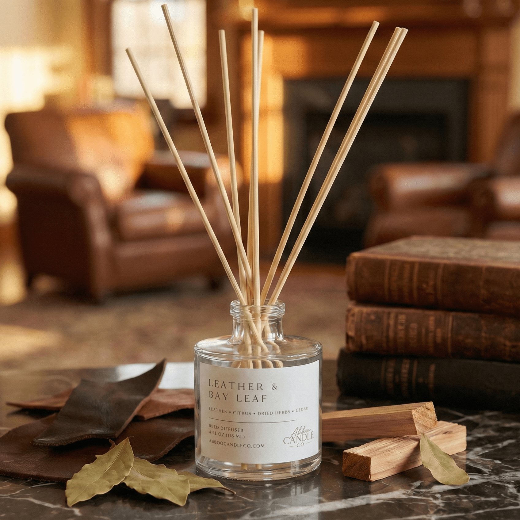 Leather Bay Leaf reed diffuser on marble surface with leather books