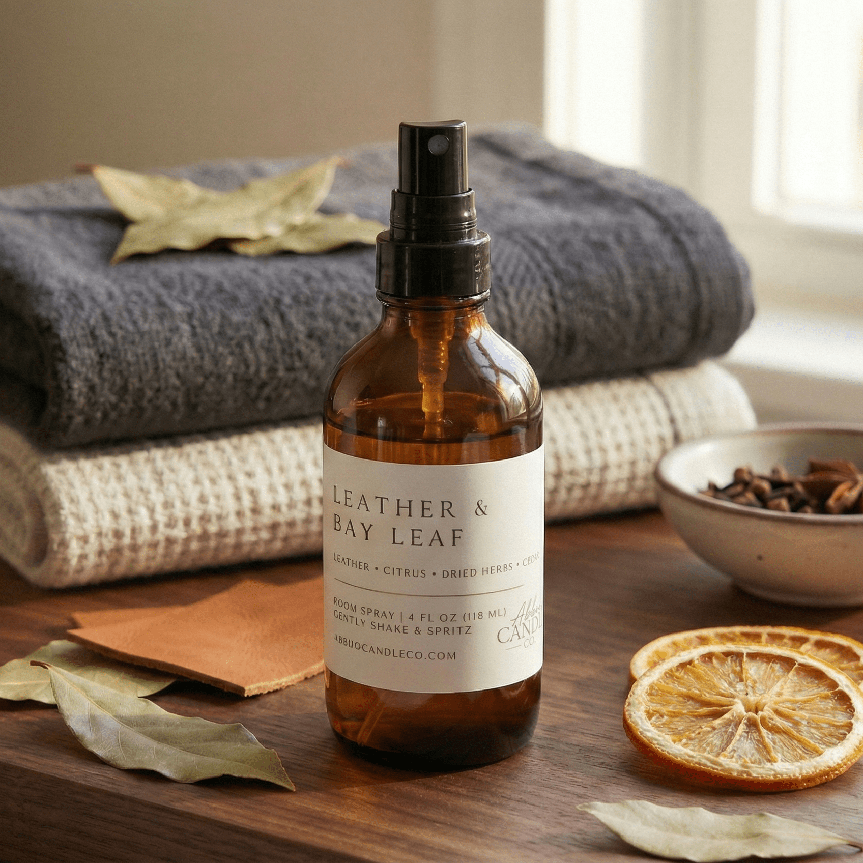 leather bay leaf room spray with soft blankets and dried citrus