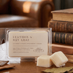 Abboo Candle Co. leather and bay leaf wax melts on a wooden surface with books in the background