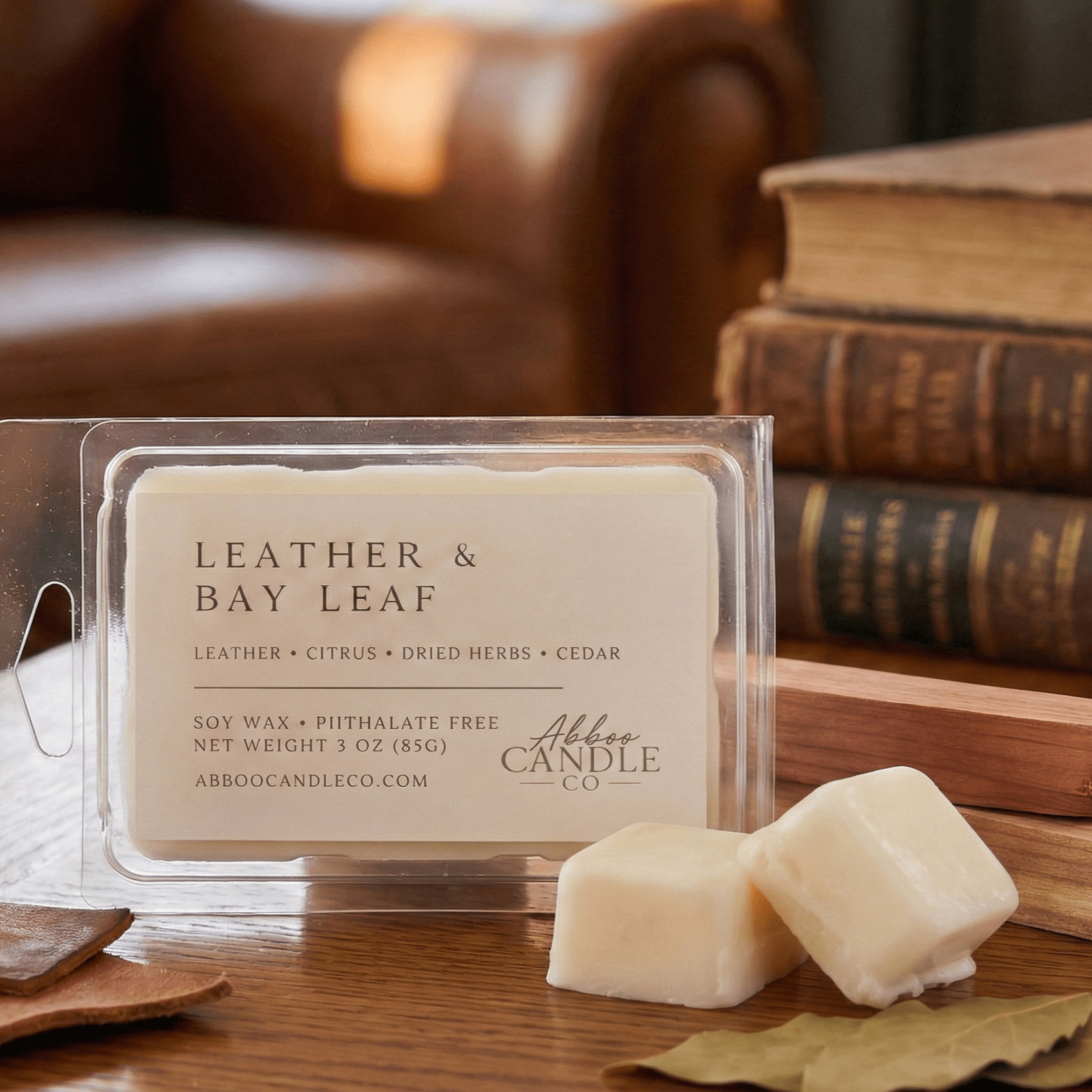Abboo Candle Co. leather and bay leaf wax melts on a wooden surface with books in the background