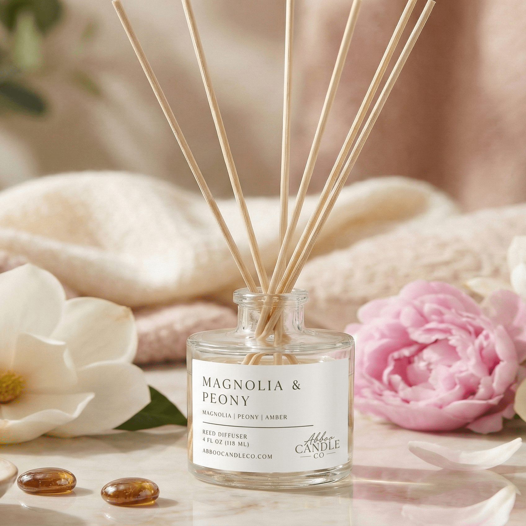 magnolia peony reed diffuser with peony and magnolia blossoms and a soft blanket