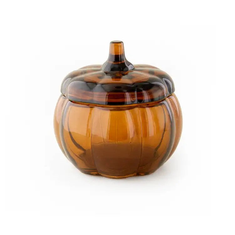 An amber glass pumpkin-shaped lidded candle with a ribbed design and a small stem, shown on a plain white background.