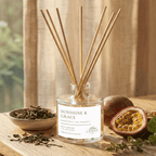 Reed diffuser labeled 'Sunshine & Grace' on a wooden surface with dried herbs and a passion fruit.